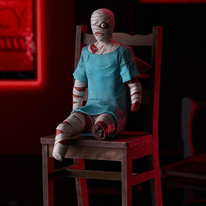 Full-body promotional shot of the POP UP PARADE Swacchao! Curly figure sitting on a miniature wooden chair under atmospheric red lighting.