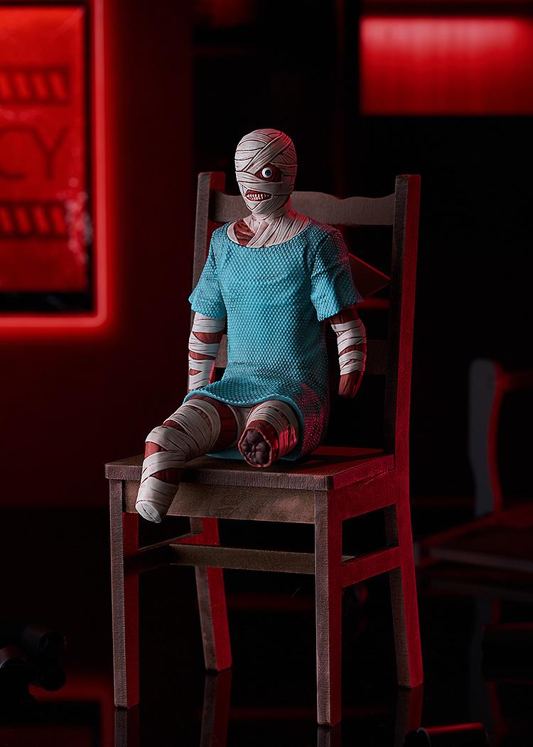 Full-body promotional shot of the POP UP PARADE Swacchao! Curly figure sitting on a miniature wooden chair under atmospheric red lighting.