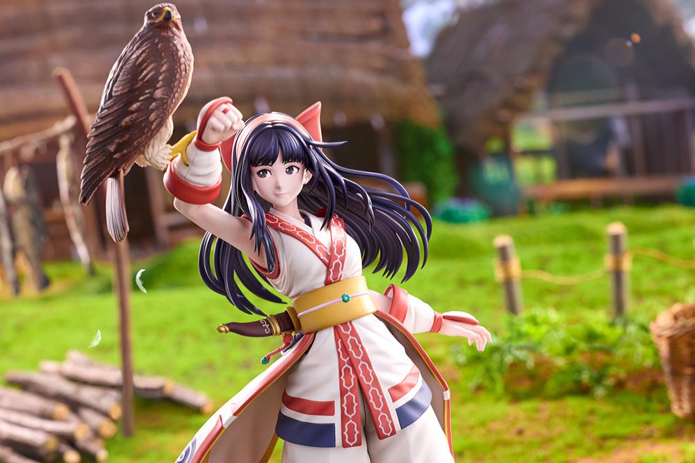 Mid-shot view of Nakoruru figure under warm outdoor lighting with an Ainu-style village backdrop