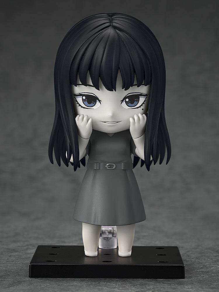 Studio shot of Tomie Nendoroid figure with hands to cheeks and a subtle smiling expression.