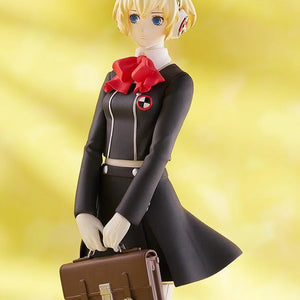 Close-up on the torso and face of the Aigis figure, highlighting the details of her black uniform, red bow, and the brown school bag.