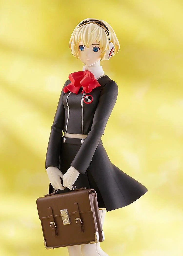 Close-up on the torso and face of the Aigis figure, highlighting the details of her black uniform, red bow, and the brown school bag.