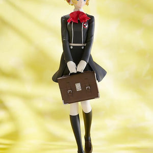 Full view of the Pop Up Parade Aigis figure against a bright yellow background, showing her black school uniform and red bow tie.