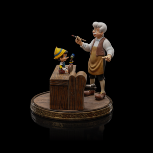A front view of the Pinocchio and Geppetto Art Scale 1/10 statue by Iron Studios, showing Jiminy Cricket on Pinocchio’s foot on the workbench.