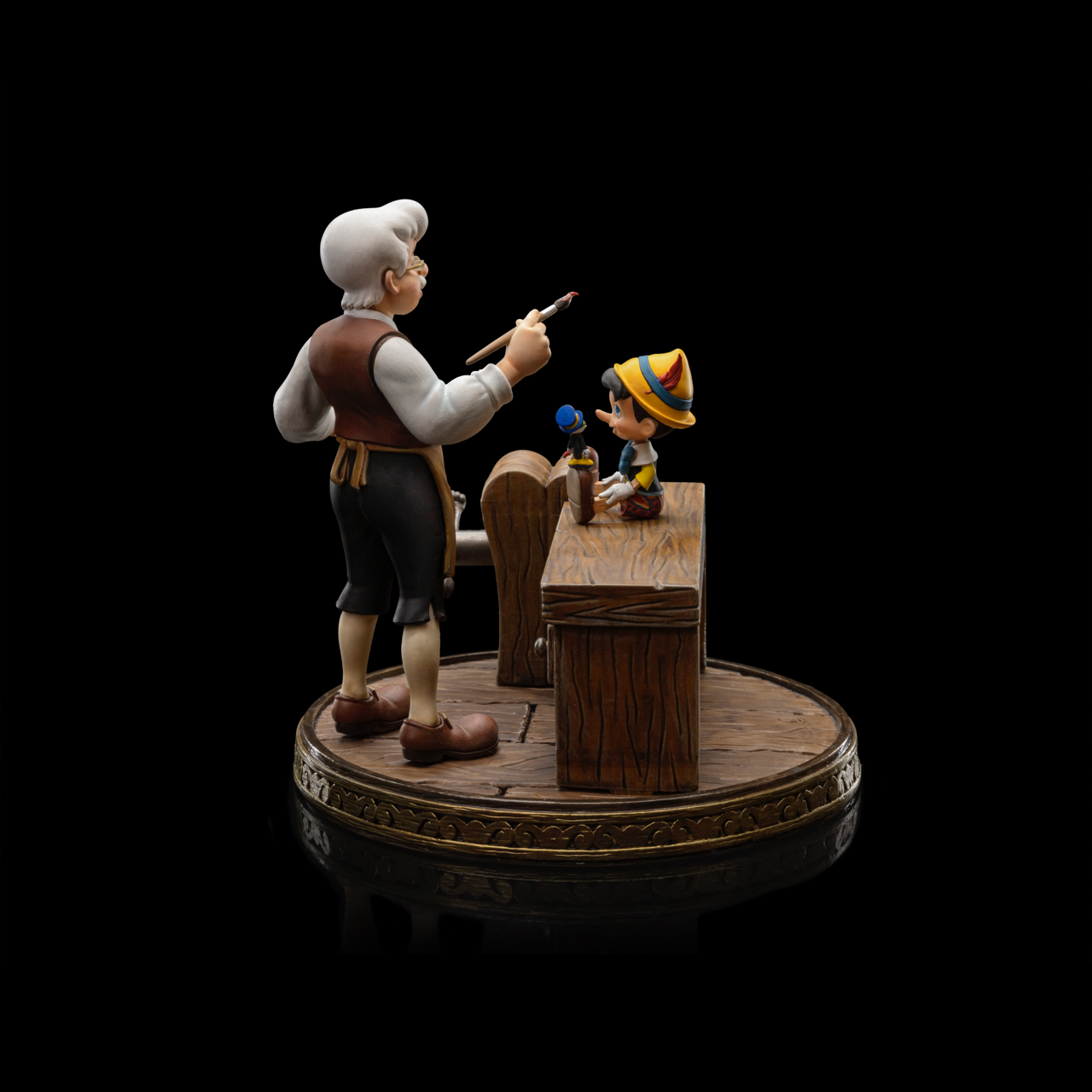 A side-angled shot of the Pinocchio Art Scale 1/10 statue, highlighting the hand-painted details of the characters and the wooden workbench.