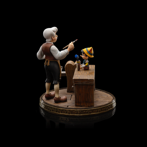 A side-angled shot of the Pinocchio Art Scale 1/10 statue, highlighting the hand-painted details of the characters and the wooden workbench.