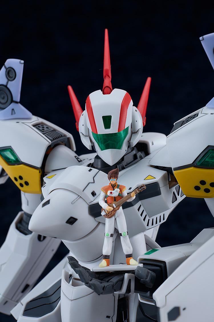 Close-up focus shot of the VF-19P Excalibur model kit's chest and head unit, holding the miniature 1/72 scale Basara Nekki figure with his guitar standing on its open robotic palm.