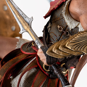 Close-up on Alexios' hand gripping the broken spear, detailing his golden forearm armor and leather skirt (pteruges).