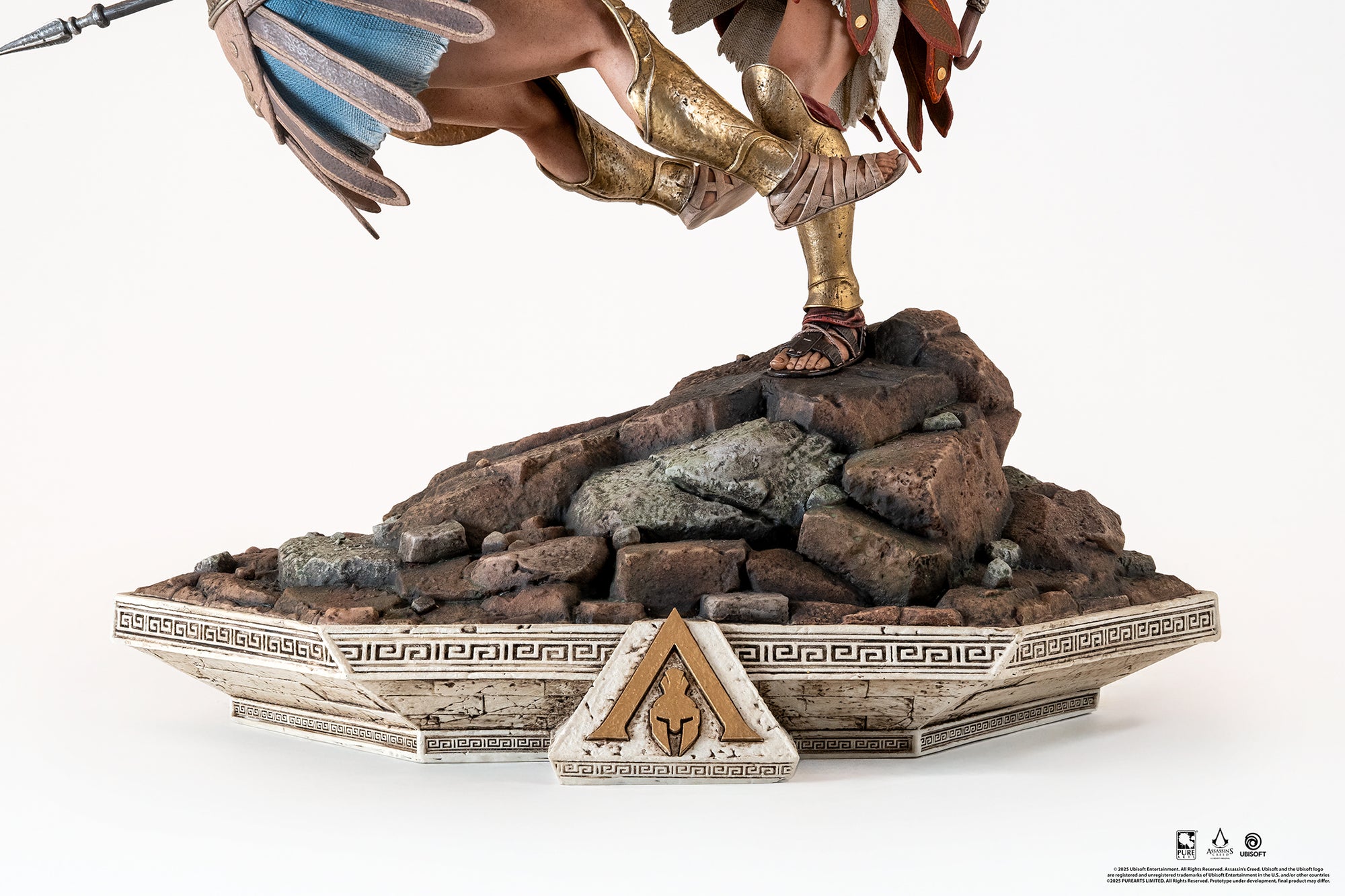 Close-up of the diorama base, highlighting the rugged rocky terrain and the decorative Greek architecture featuring the Assassin's Creed Odyssey logo.