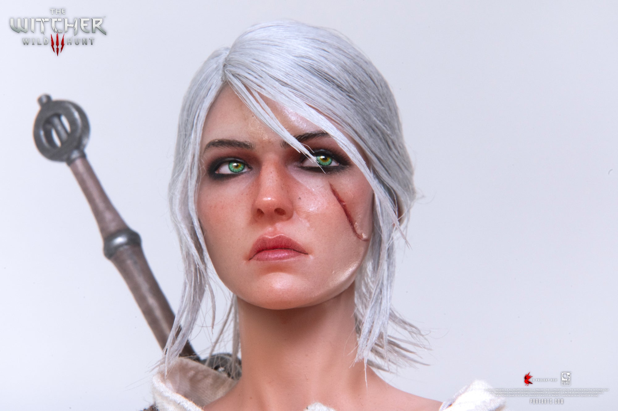 An intense close-up of Ciri's face, clearly showing the scar across her left cheek and the movable green eyes.