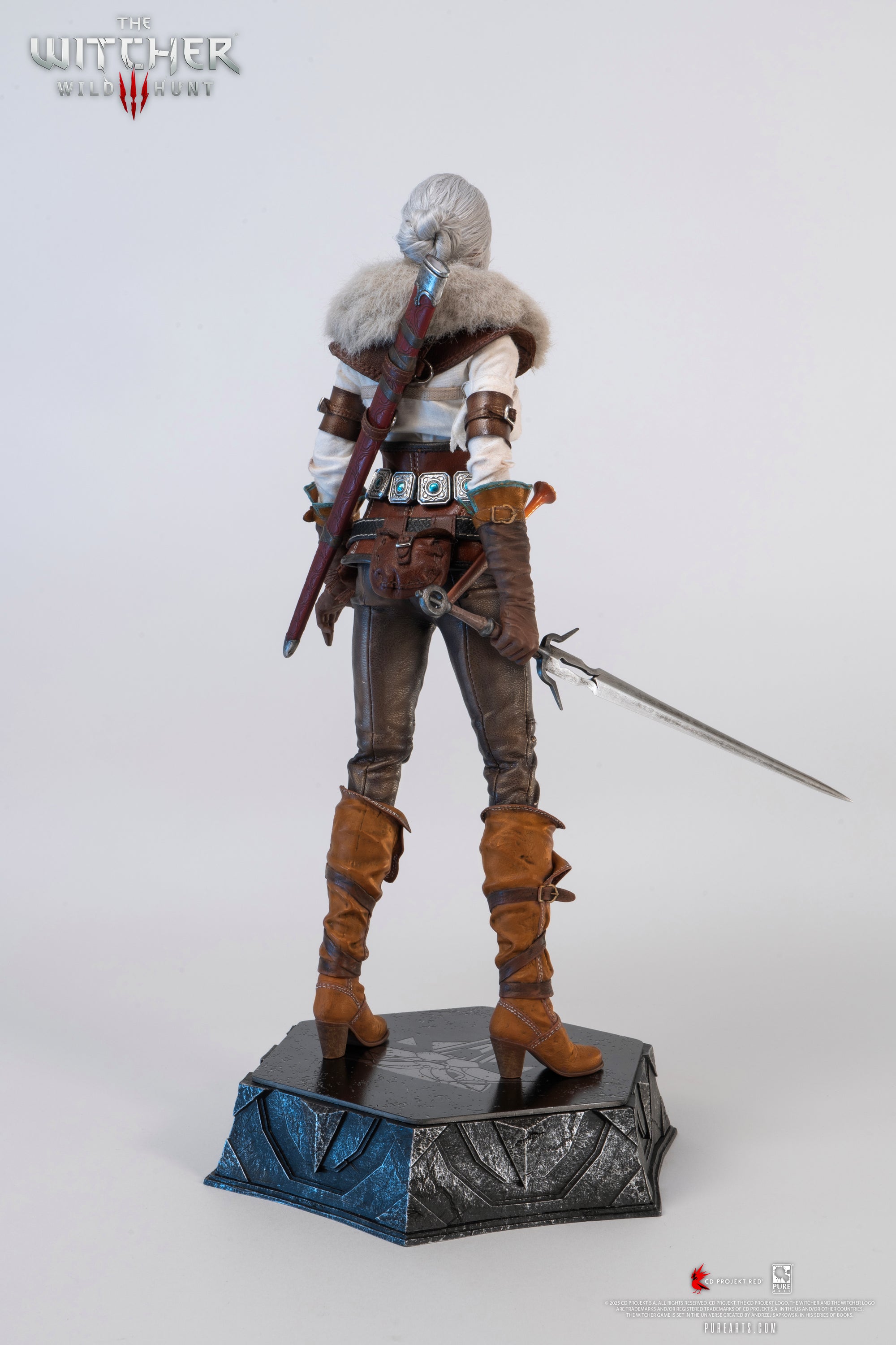 A three-quarter rear view of the Ciri figure, showing the extended metal sword and the detailing of her leather pants.
