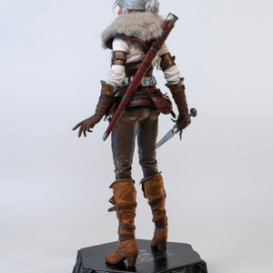 Rear view of the Ciri figure wearing the fur mantle, with her hand resting on the dagger's hilt.