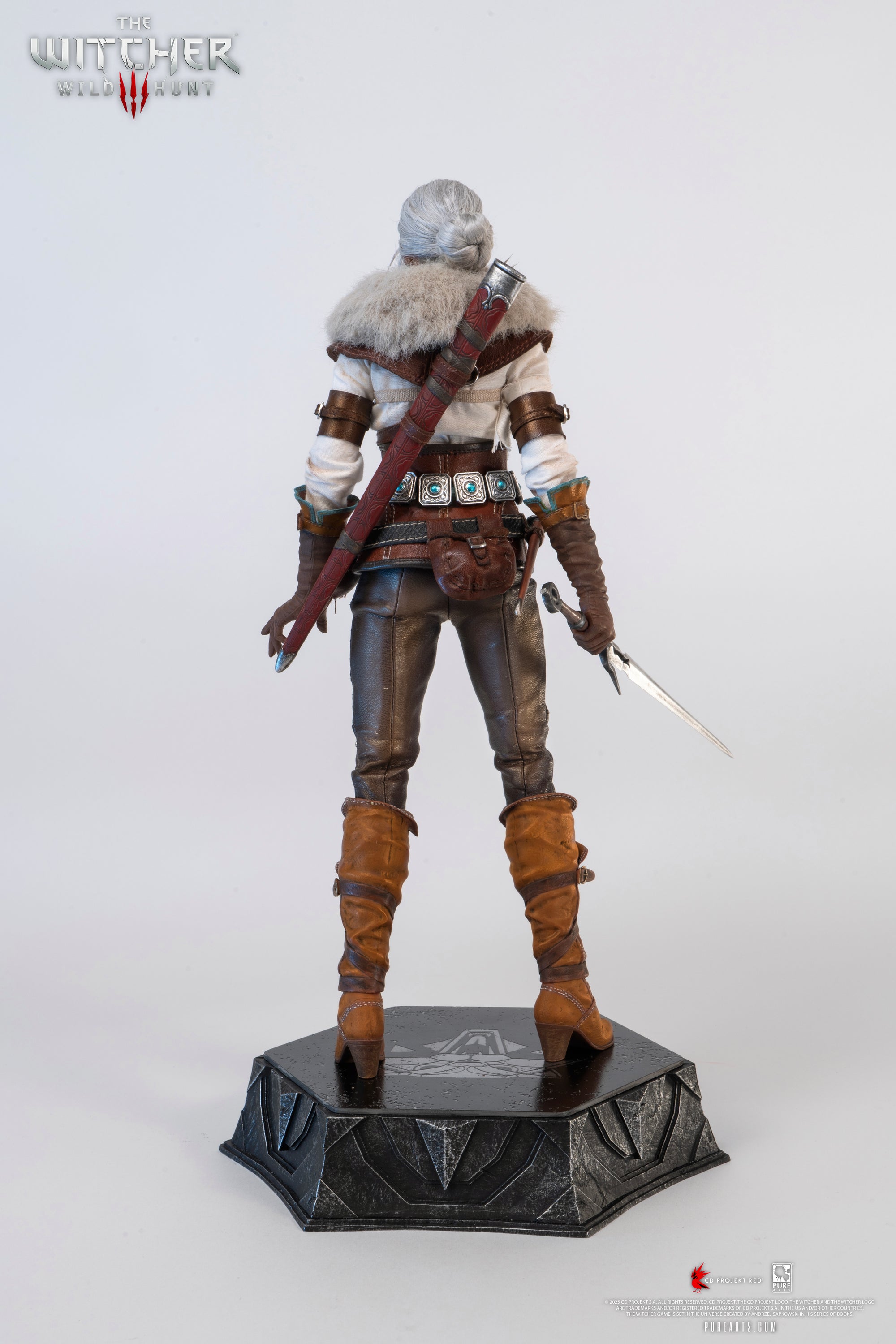 Rear view of the Ciri figure, with the fur mantle on, drawing her long metal sword from its scabbard.