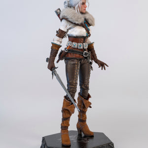 A slightly angled frontal view of the Ciri figure, wearing the fur mantle and holding the metal sword down in front of her.