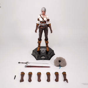 Laydown shot of the Ciri figure with all major accessories detached: sword, scabbard, dagger, fur mantle, swappable hands, and adjustment tool.