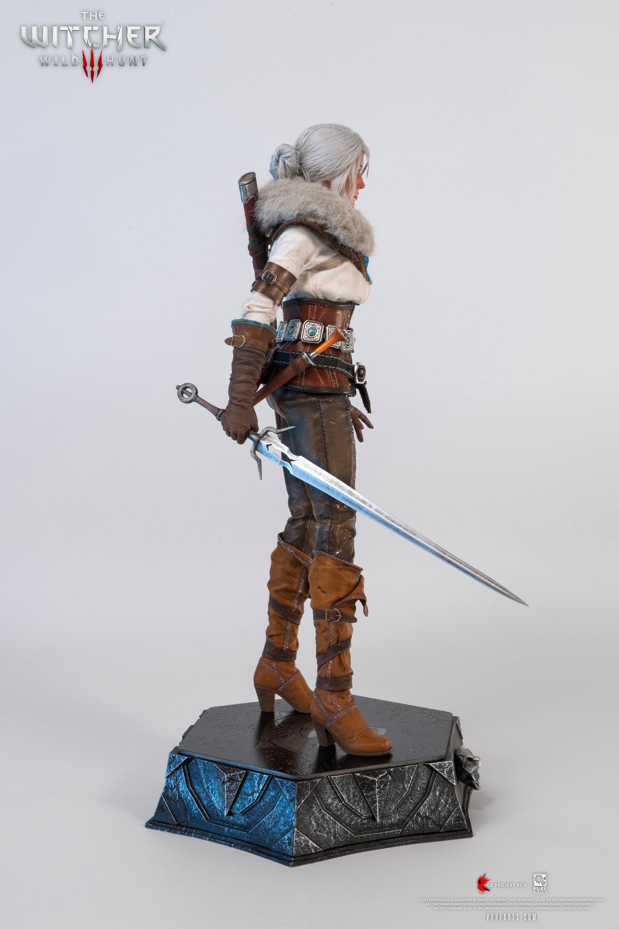 Side profile of the Ciri figure holding the metal long sword extended down by her side.