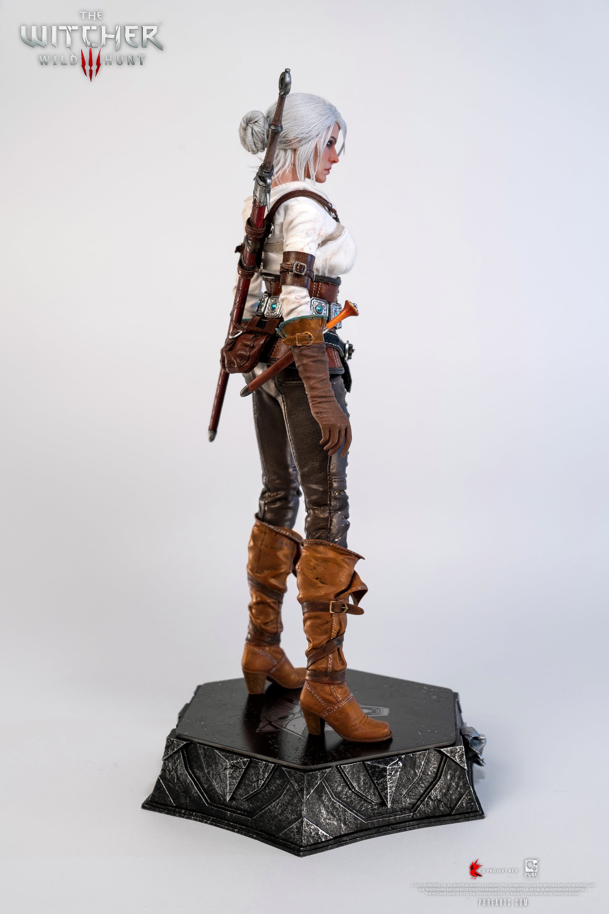 A straight side view of the Ciri figure, emphasizing the layers of her clothing and the Witcher wolf medallion on the base.