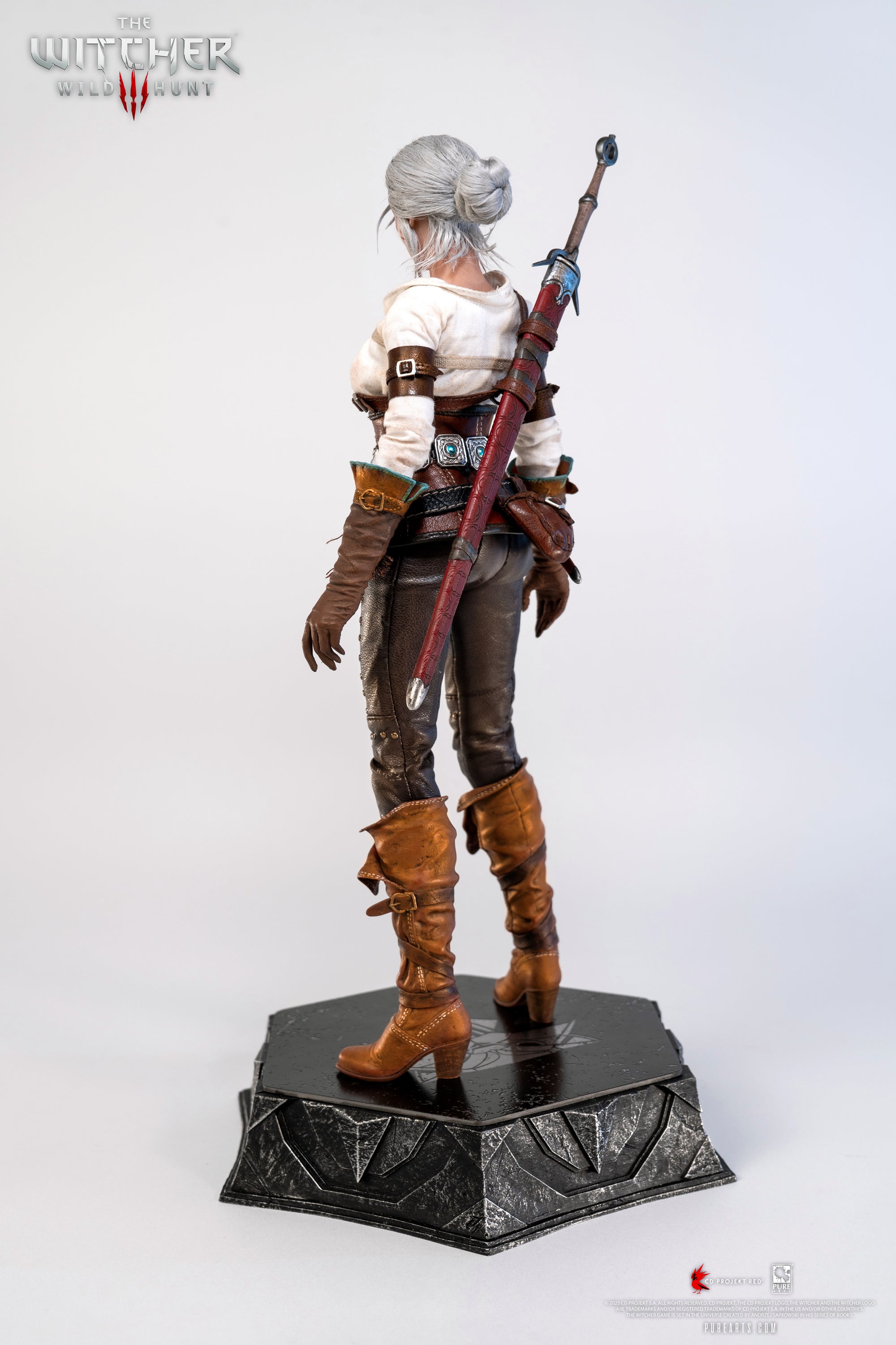 A three-quarter rear view of the Ciri figure, showcasing the back of her scabbard and her gray bun hairstyle.