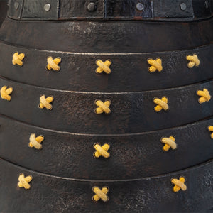 A close-up shot of the layered, textured black armor plates of the neck guard on the PureArts Yasuke helmet, tied together with yellow cords.