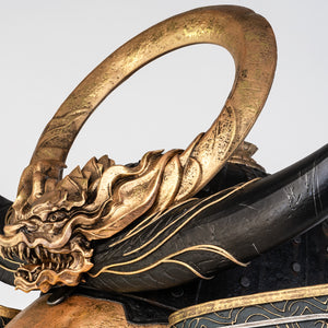 ide view of the PureArts Yasuke helmet, highlighting the curved black horns and the detailed gold dragon crest at the front.