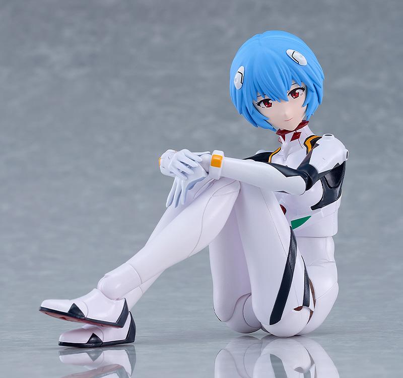 PLAMATEA Rei Ayanami action model figure in a seated pose hugging her knees on a gray studio surface.