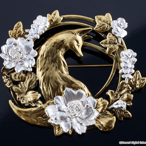 Silent Hill f brass brooch replica displayed on a dark reflective surface, highlighting the detailed fox silhouette and silver flowers.