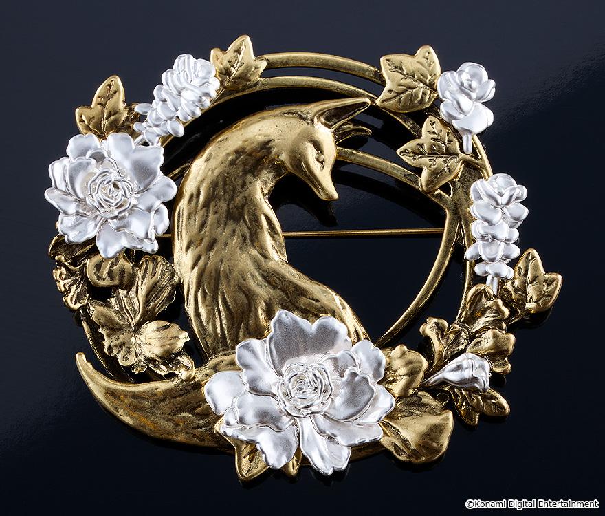 Silent Hill f brass brooch replica displayed on a dark reflective surface, highlighting the detailed fox silhouette and silver flowers.
