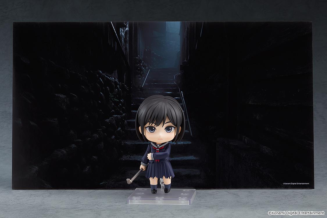 Promotional display shot of the Hinako Shimizu Nendoroid figure set against a dark, atmospheric Silent Hill f alleyway backdrop.