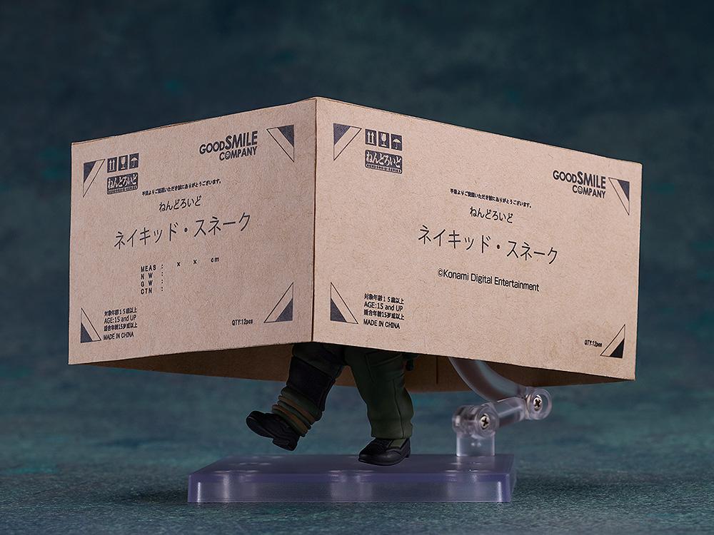 Iconic stealth pose of the Naked Snake Nendoroid hiding under a Good Smile Company cardboard box.