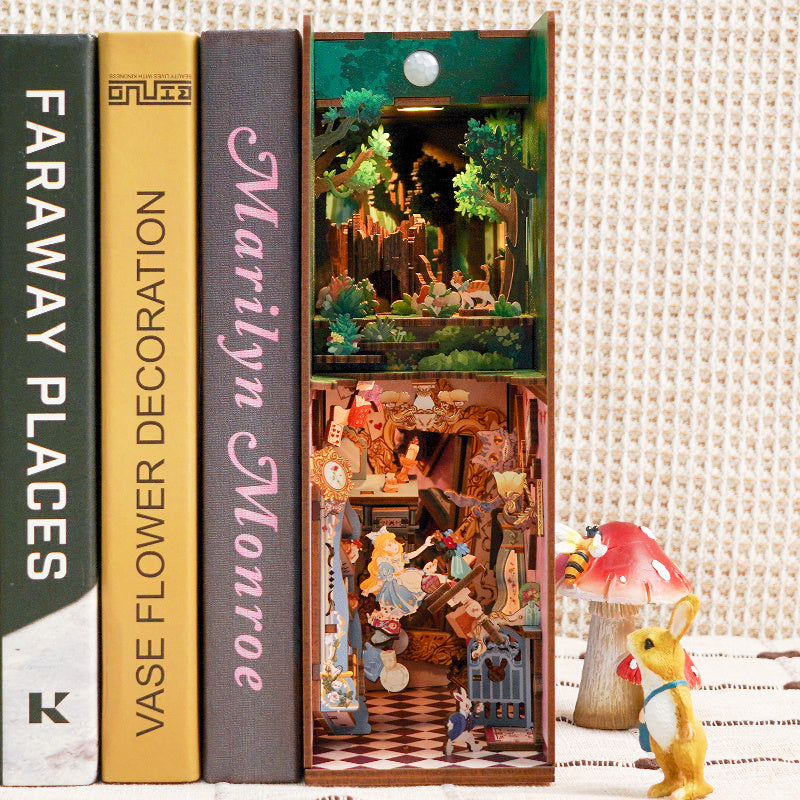 The assembled "Alice in Wonderland" book nook placed between books on a shelf, showing the whimsical figures and illuminated scene.