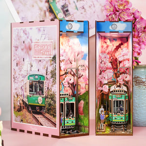 The assembled "Sakura's Travel" book nook displayed next to its front cover, emphasizing the deep perspective and warm pink glow of the scene.