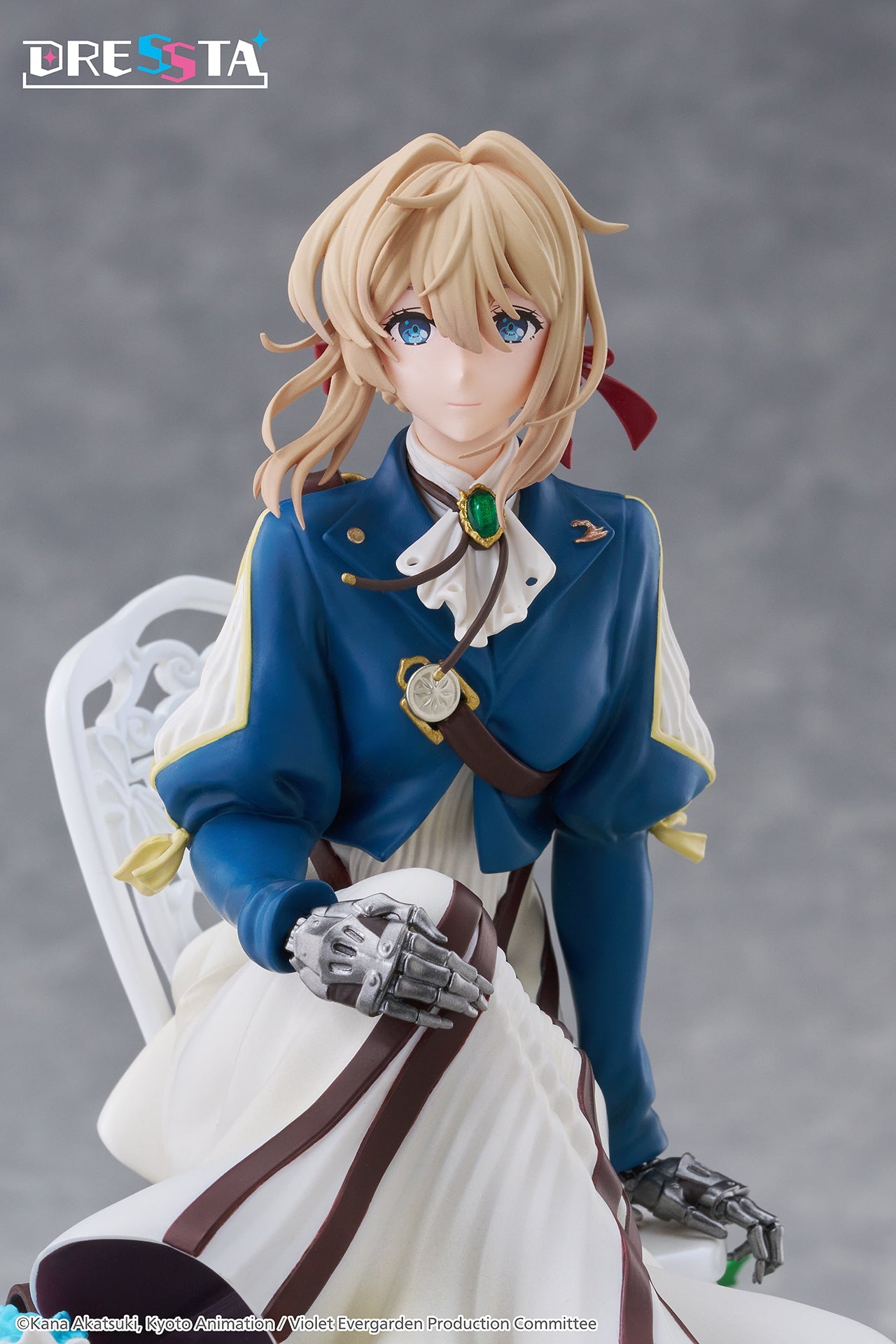Upper body close-up of Violet Evergarden figure featuring her emerald brooch, blue jacket, and metallic prosthetic hands
