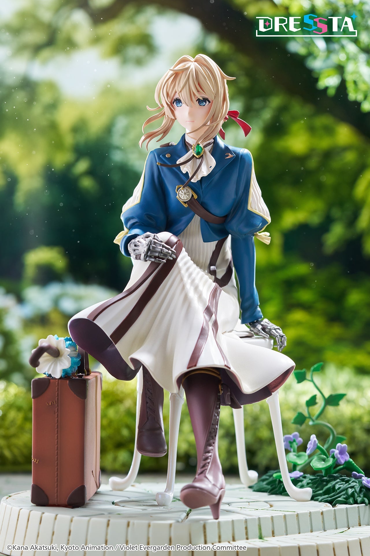 Front view diorama shot of Taito's Violet Evergarden figure set against a soft blurred green garden backdrop