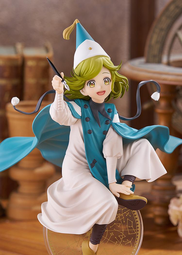 Medium shot of the Coco POP UP PARADE L figure holding her fountain pen accessory upward, set against a warm, out-of-focus laboratory background.