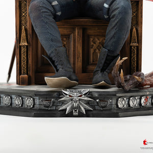 Low-angle view of Geralt's boots rested on the stone base next to Dettlaff's severed vampire arm and the wolf medallion base ornament.