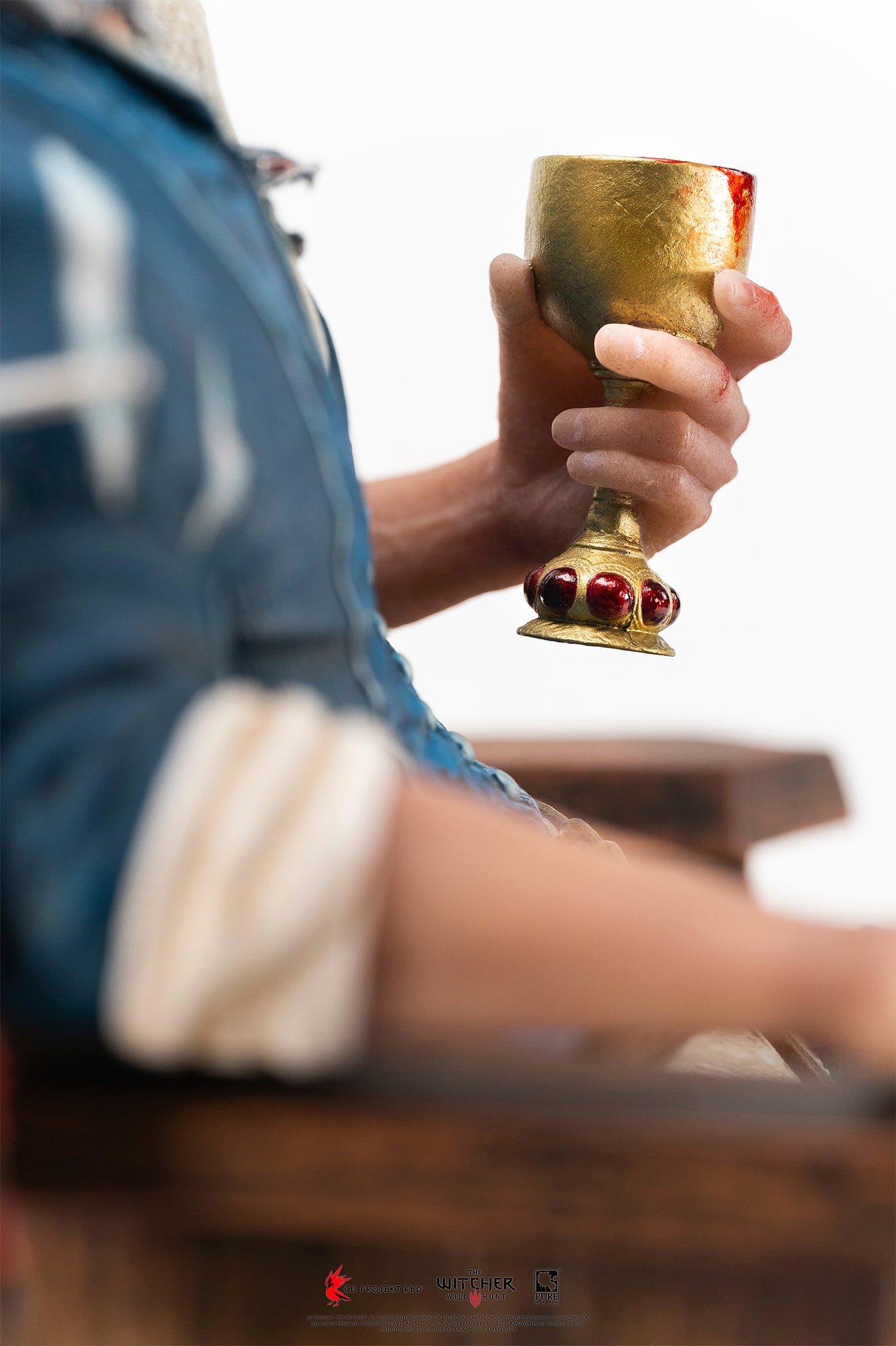 Side-angle close-up of Geralt's hand holding an ornate jewel-encrusted goblet filled with blood.