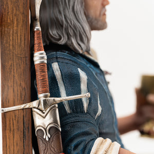 Side detail shot showing Geralt's steel sword in its leather scabbard resting against the side of the wooden throne.