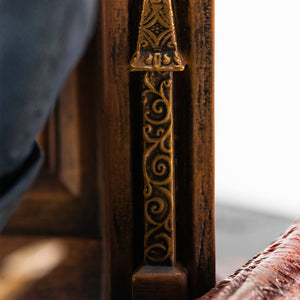 Macro view highlighting the intricate gold filigree wood carving details on the wooden throne frame.