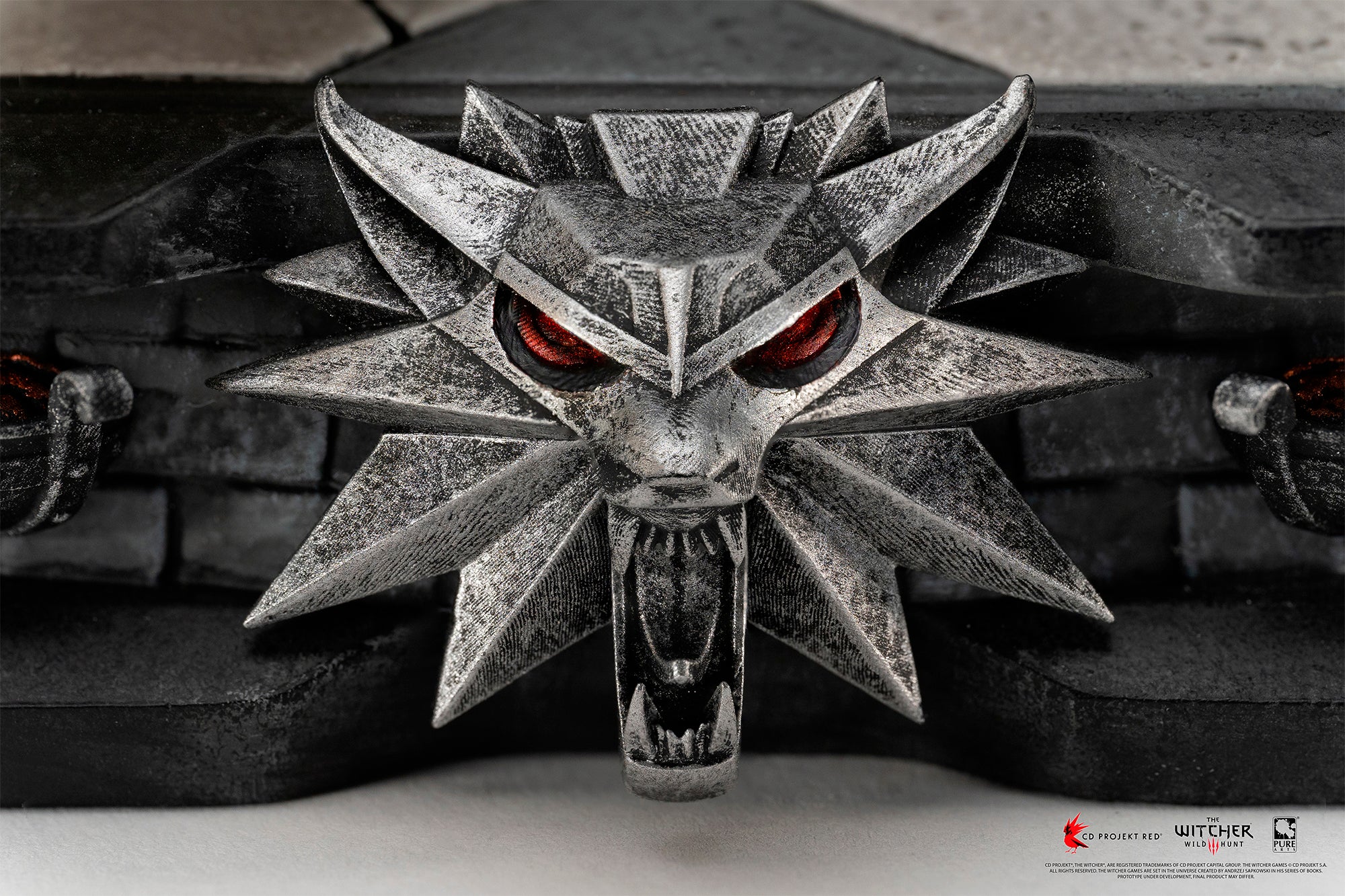 Detailed front view of the metallic Wolf School emblem relief sculpt on the base of the PureArts Geralt statue.