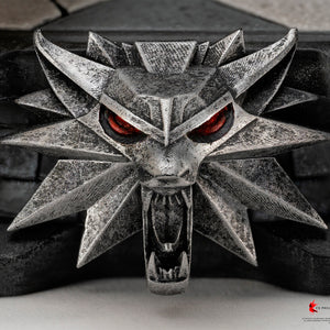 Detailed front view of the metallic Wolf School emblem relief sculpt on the base of the PureArts Geralt statue.