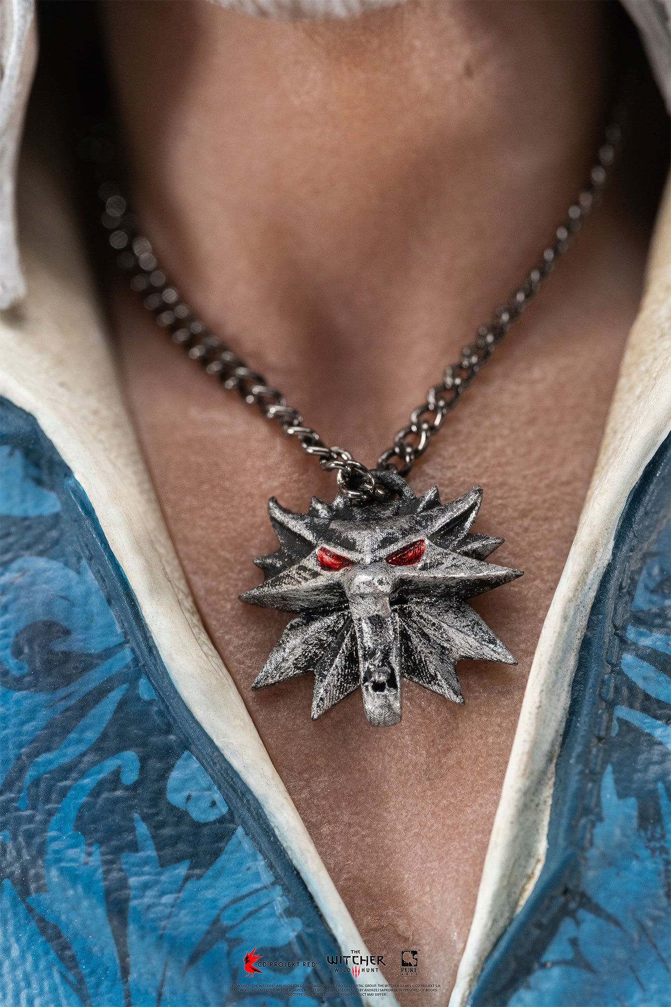 Detailed close-up shot of Geralt of Rivia's silver Wolf School medallion with glowing red eyes.