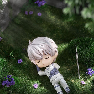 Xavier Nendoroid posed napping in a grassy field with purple flowers and his sword nearby.