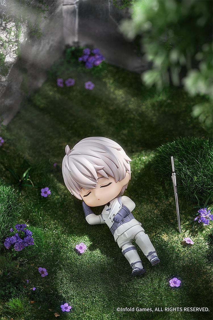 Xavier Nendoroid posed napping in a grassy field with purple flowers and his sword nearby.